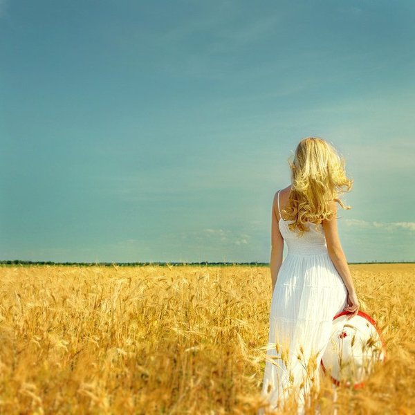Femme blonde de dos dans champ de ble ciel bleu soleil